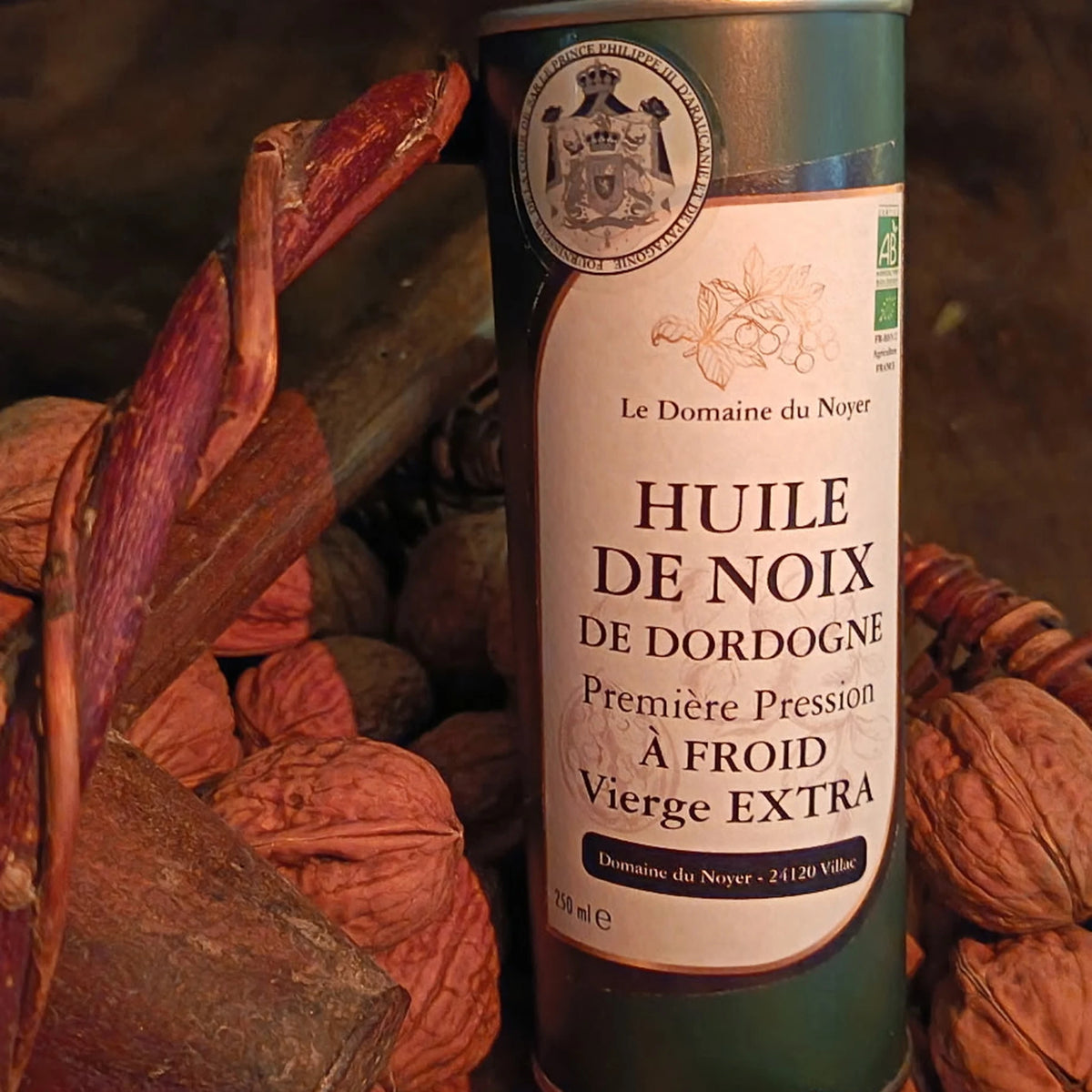 Bidon d'huile de noix bio du Domaine du Noyer posé sur un lit de noix